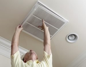 A person is sitting indoors with a mechanical fan blowing on their face.